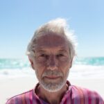 Old man looking at the camera at the beach