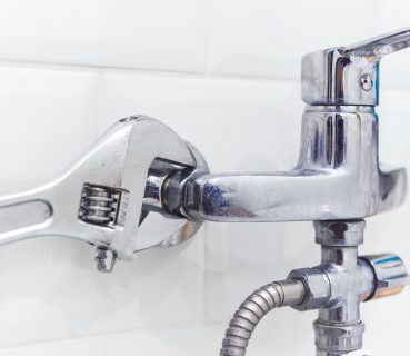Plumber uses pipe wrench for service shower mixer tap
